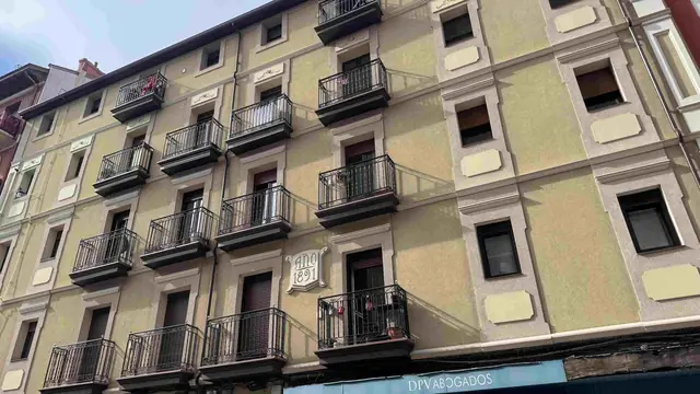 Fachada rehabilitada de un edificio de 1891 con balcones de forja en Barakaldo