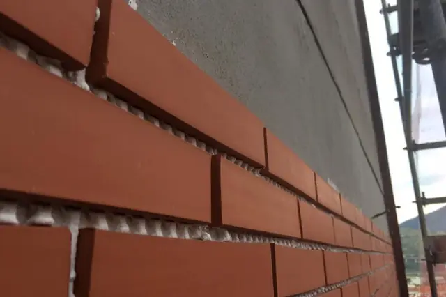 Detalle de la colocación de piezas de ladrillo en una fachada de Bilbao